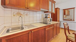 A kitchen with wooden cabinets, a stainless steel sink, a microwave, and a chair. - Studio apartment for 2 in Villa Armin (Rovinj)
