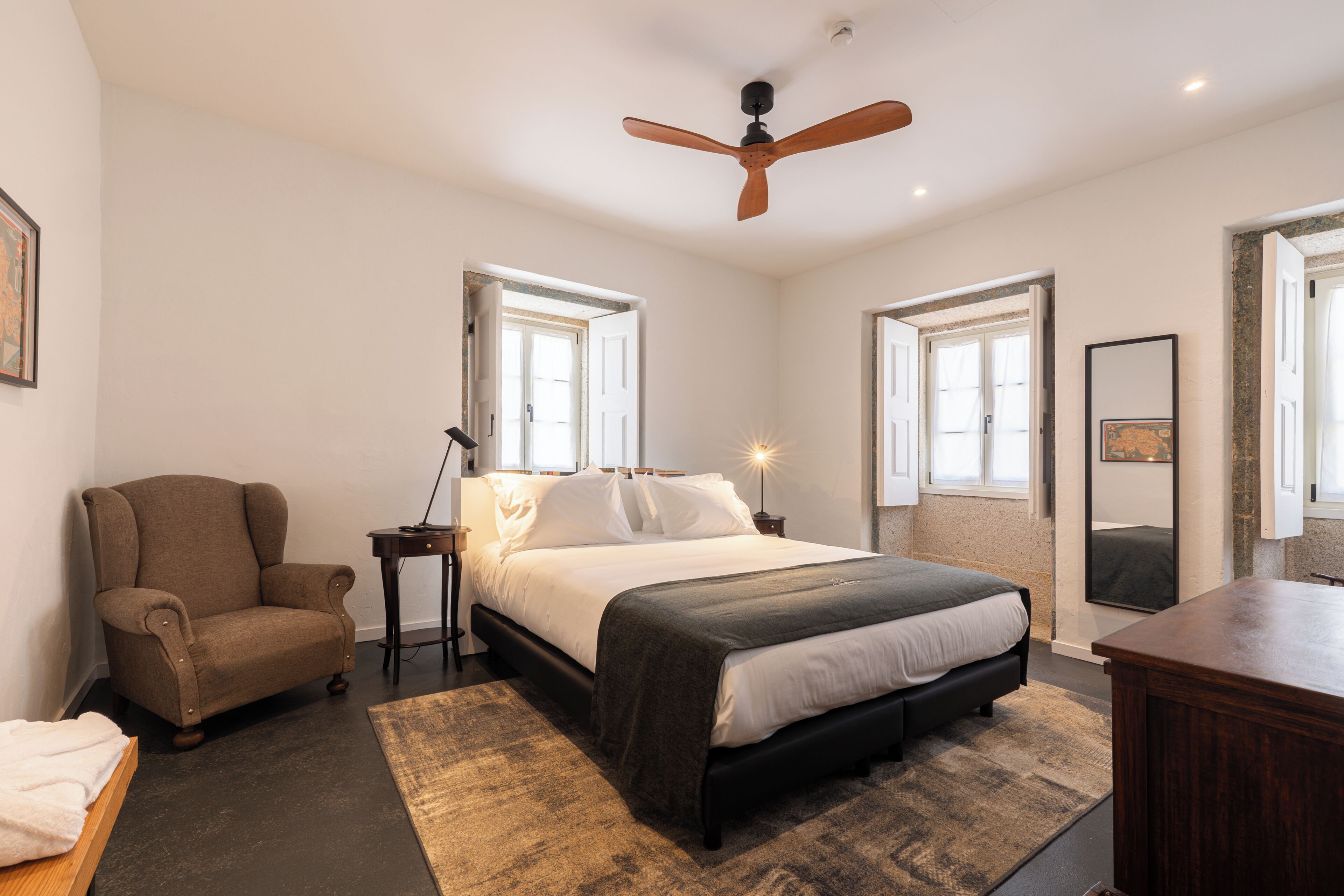 Une chambre à coucher avec un lit, une chaise, un bureau et un ventilateur de plafond.