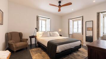 Une chambre à coucher avec un lit, une chaise, un bureau et un ventilateur de plafond.