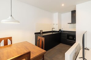 A modern kitchen with a black countertop, white backsplash, and a wooden dining table with chairs. - Casa Nova Farmhouse (Braga)