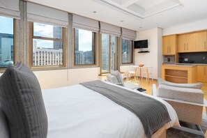 Une chambre d’hôtel moderne équipée d’un grand lit, d’un bureau, d’une chaise et d’une kitchenette.
