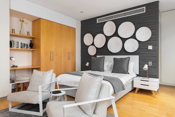 Une chambre à coucher moderne, comprenant un lit, des tables de chevet, une chaise, un bureau et une bibliothèque.