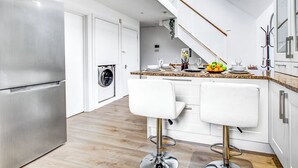 A modern kitchen with stainless steel appliances, a wooden floor, and a central island with bar stools. - Wimbledon/Discount/Close to AELTC&Station/En-Suite (London)