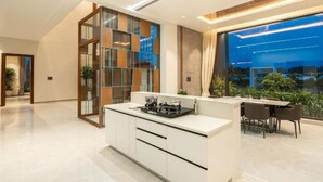 Una cocina moderna con una isla central, un comedor con mesa y sillas, y ventanas amplias con vistas al exterior.