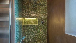 Eine Dusche mit Wänden aus Mosaikfliesen und einer Metallduschkabinentür.