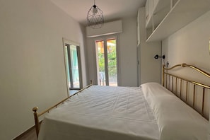 Un dormitorio con una cama, una lámpara colgante de diseño, una ventana y una puerta que da a un espacio exterior.