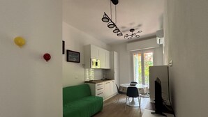 Una cucina compatta con mobili bianchi, un tavolo da pranzo e un divano verde.