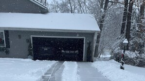 A snow-covered driveway leading to a garage.