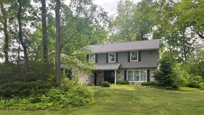 A two-story house with a stone facade, a front porch, and a well-maintained lawn.
