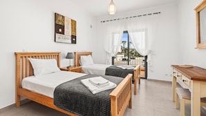 A bedroom with two beds, a desk, and a view of the outside. - Coastal Charm Apartment (Lagos)