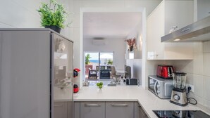 Eine moderne Küche mit Einbauofen, Kaffeemaschine und Mixer. Blick auf einen Essbereich mit Tisch und Stühlen.