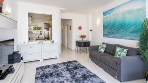 Ein modernes Wohnzimmer mit grauem Sofa, schwarzem Teppich und einer Küche im Hintergrund.
