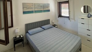 Ein Schlafzimmer mit Bett, Nachttisch, Kommode, Spiegel und einem Bild an der Wand.