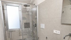 Ein modernes Badezimmer mit Duschkabine aus Glas, Toilette und Waschbecken.