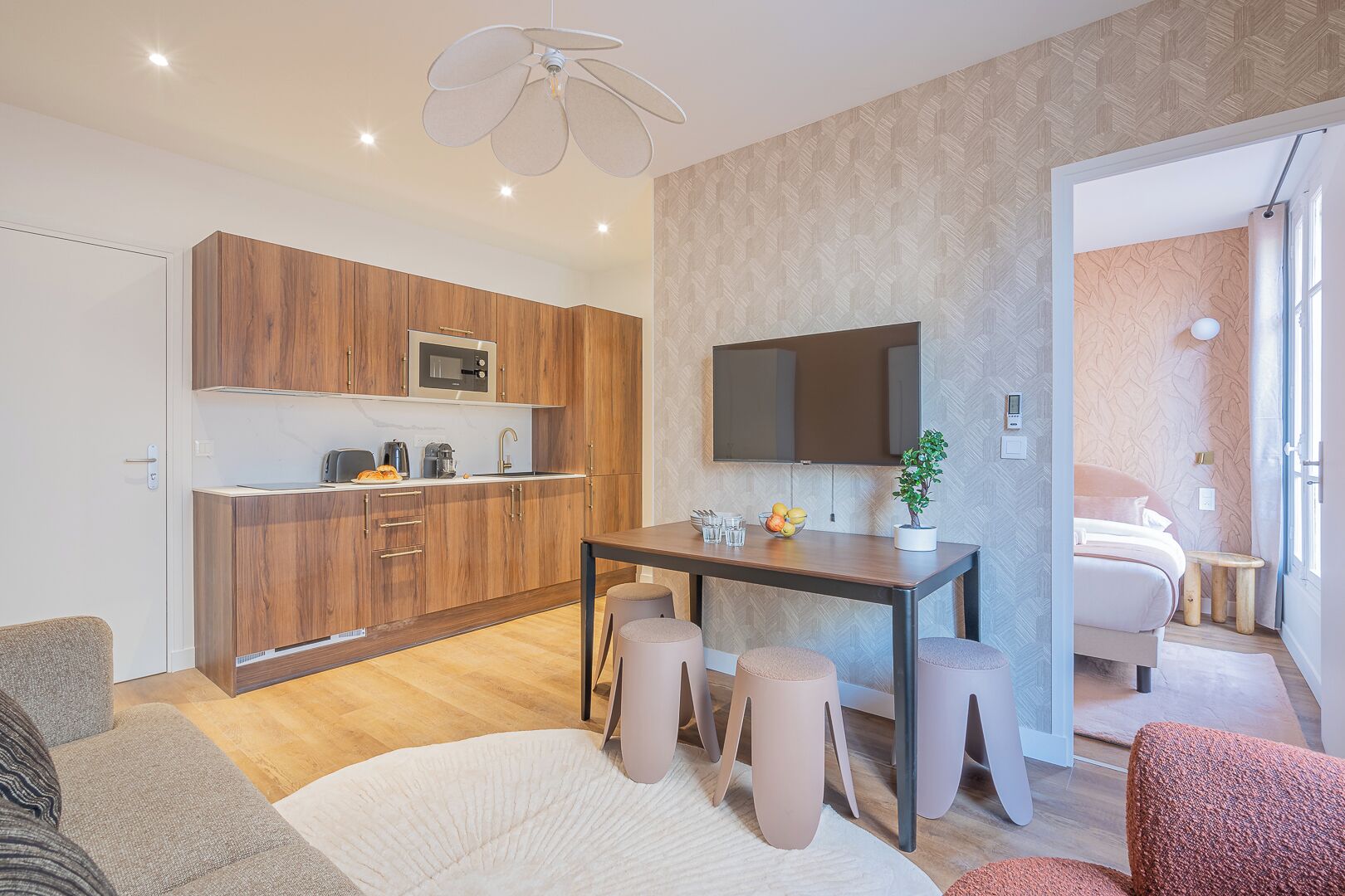 Una cocina moderna con armarios de madera, microondas y una zona de comedor con taburetes.