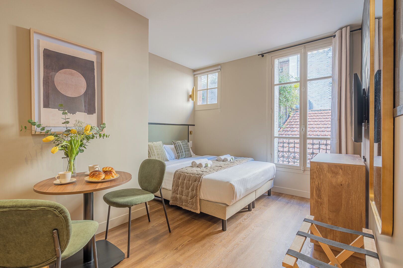 A bedroom with a bed, a small table with a vase of flowers, a chair, and a wooden cabinet.