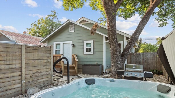 A backyard with a hot tub, a wooden fence, a grill, and a house. - Private Hot - Private Yards - WIFI (Fredericksburg)