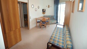 Ein kompakter Raum mit Bett, einem kleinen Tisch mit Stühlen, einer Couch und einem Fernseher an der Wand.