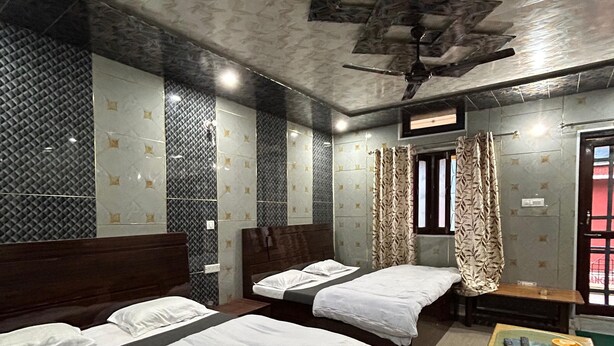Habitación de hotel con dos camas, una mesita con superficie de vidrio y un ventilador de techo.