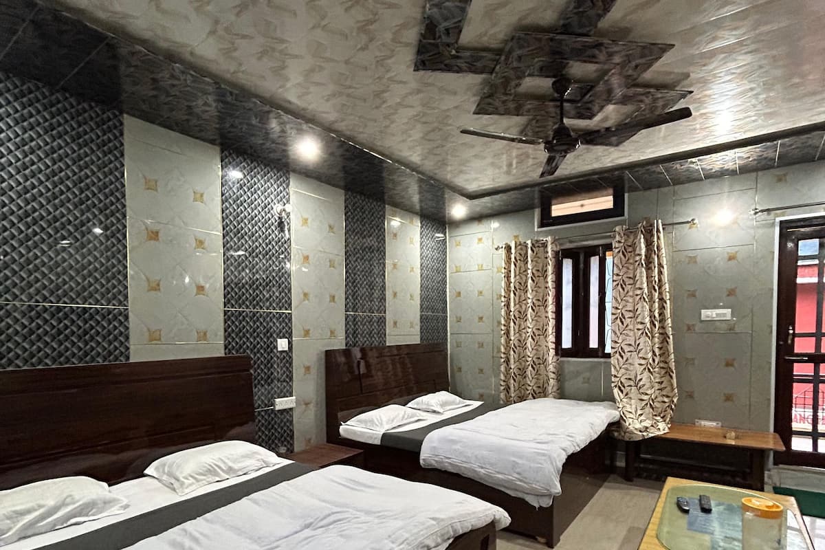 A hotel room with two beds, a small table with a glass top, and a ceiling fan.