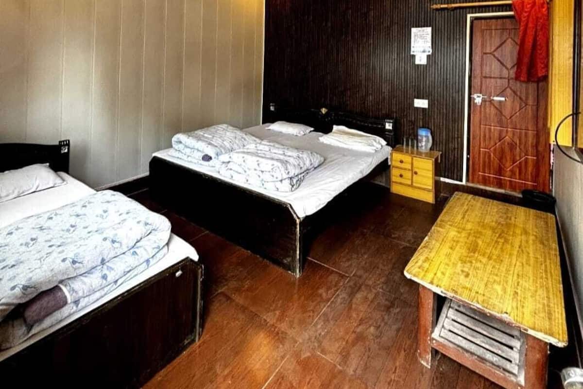 A bedroom with two beds, a wooden floor, a ceiling fan, and a small wooden table.