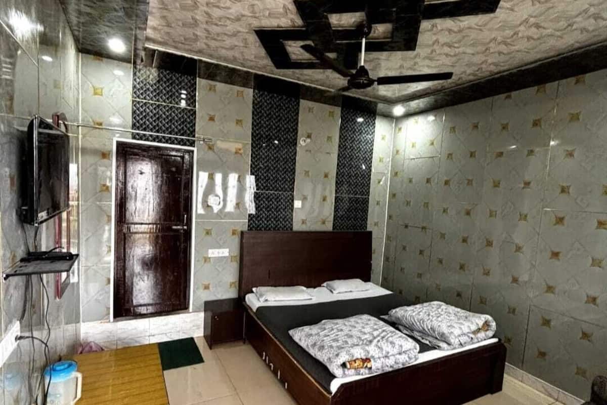 A bedroom with a bed, a wooden bench, a TV, and a ceiling fan.