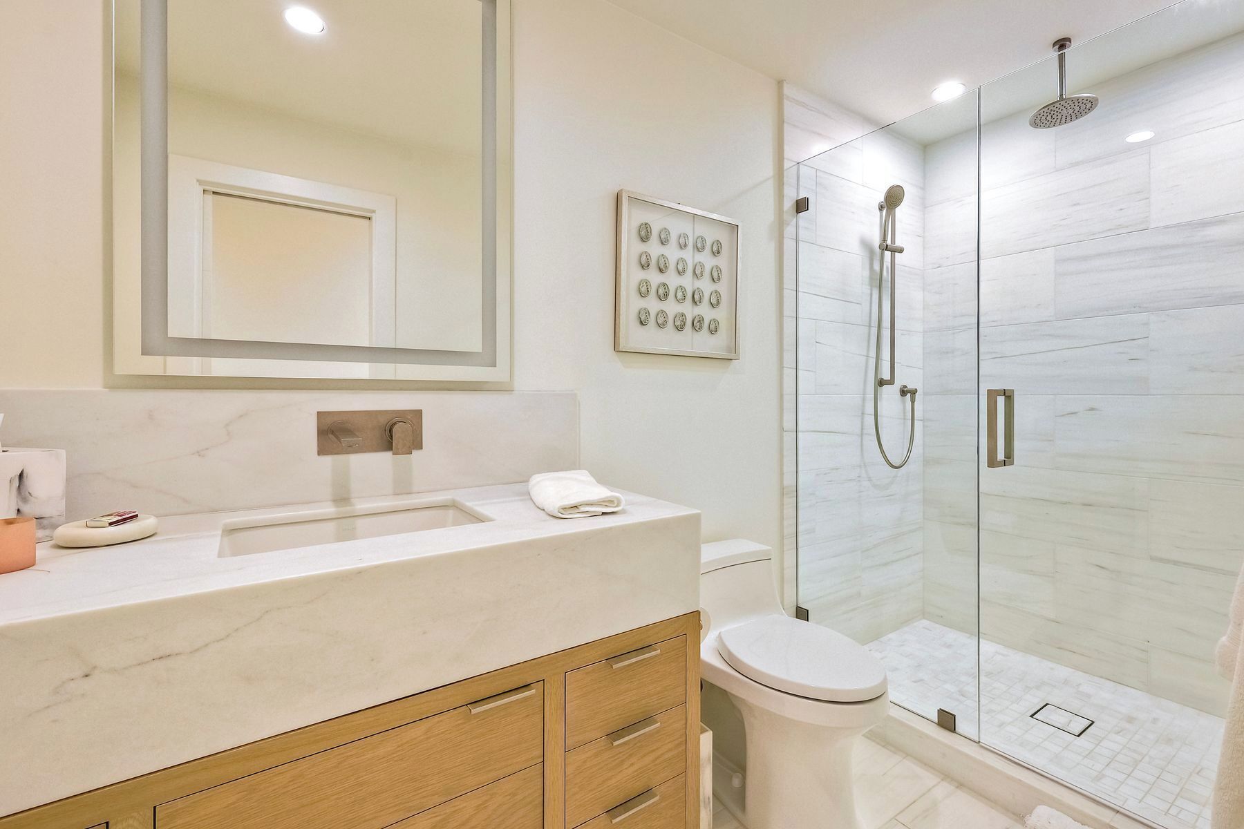 Une salle de bain moderne avec un lavabo en marbre, des toilettes et une douche à parois de verre.