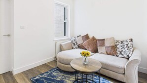 A modern living room with a sofa, a round coffee table, and a window. - 4br4ensuite-garden-w&d-closetocitycentre (Reading)