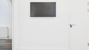 A room with a white wall, a door with a purple handle, and a flat-screen TV mounted on the wall. - 4br4ensuite-garden-w&d-closetocitycentre (Reading)