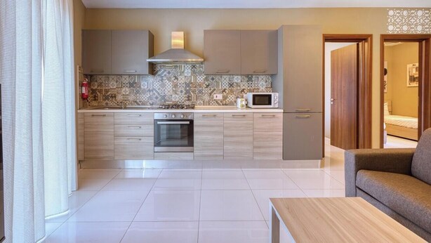 A modern kitchen with a gas stove, oven, microwave, and a patterned backsplash.