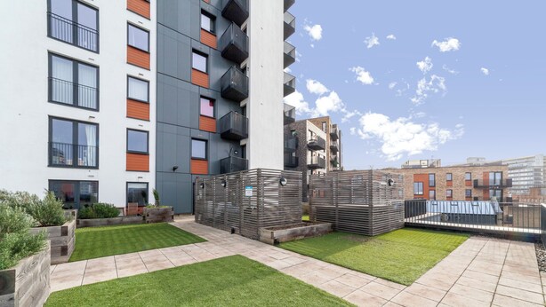 A modern apartment building with balconies, a rooftop garden, and a clear sky. - Nice Apartment in Woolwich (London)