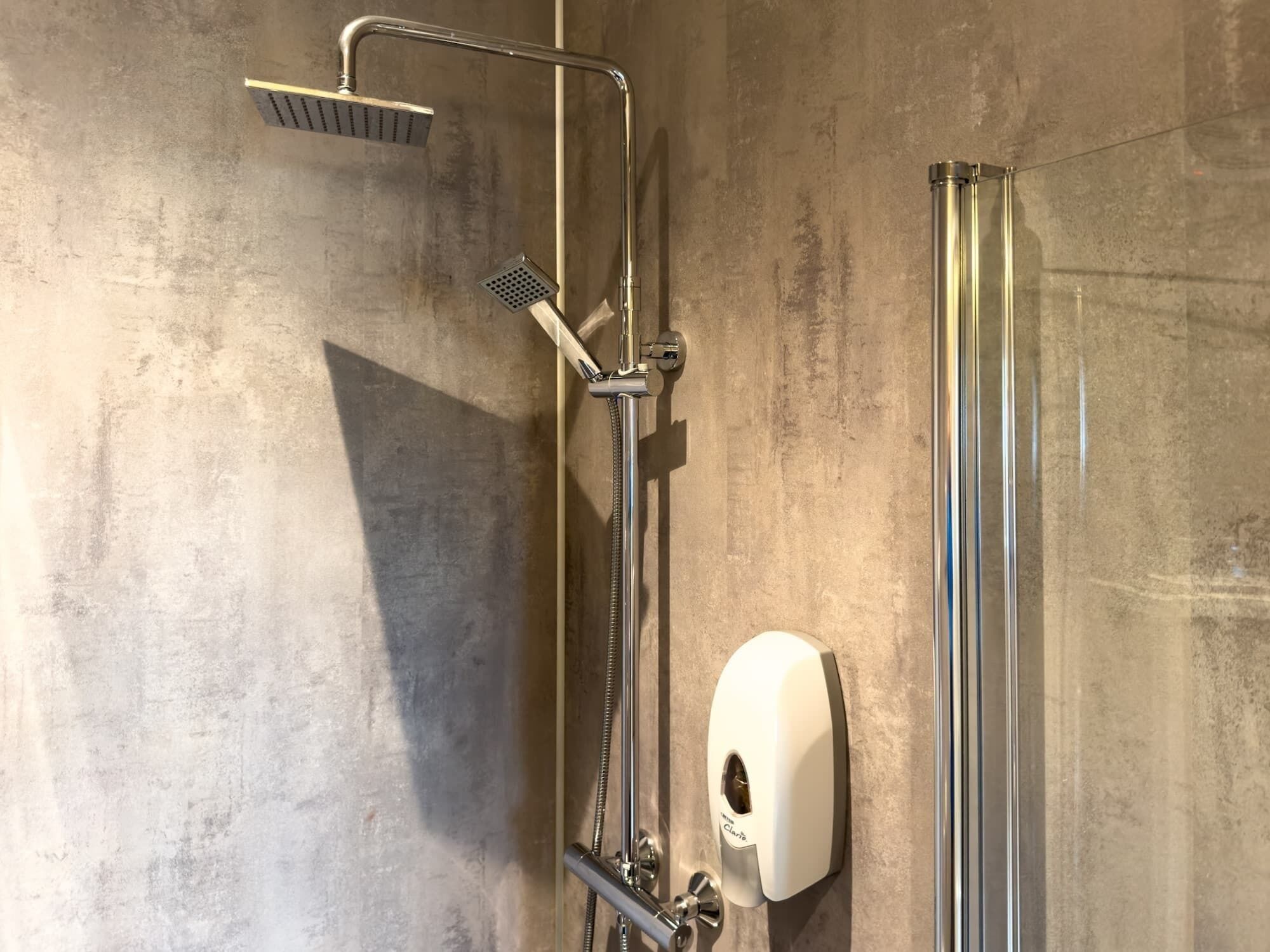 Eine moderne Dusche mit Handbrause und Wandarmatur.