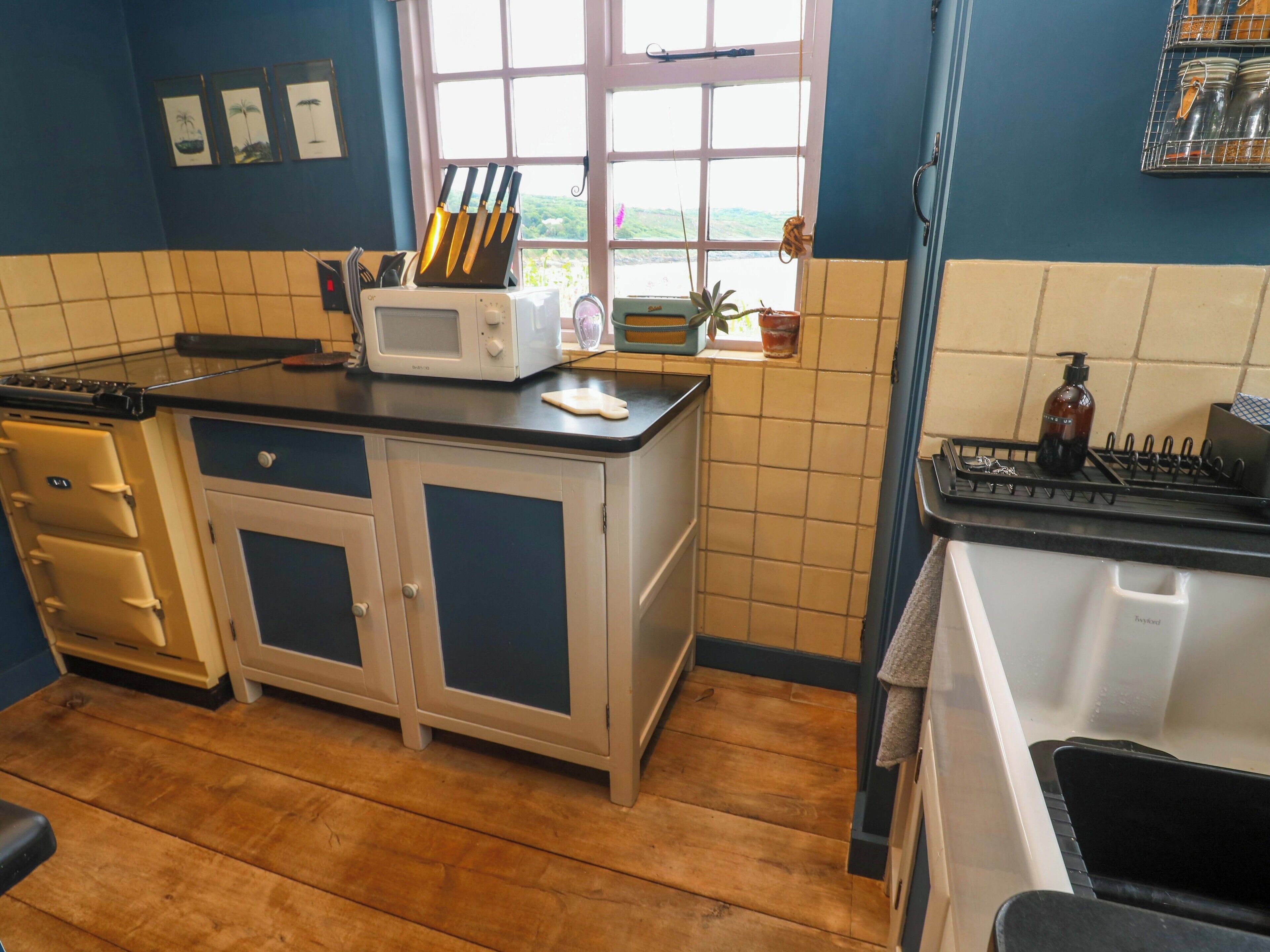 A kitchen with a microwave, a knife block, and a window with a view.
