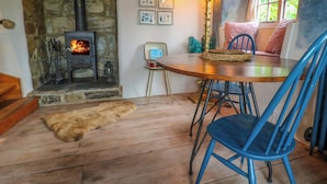 Una habitación acogedora con chimenea de piedra, una mesa de comedor con sillas y una ventana con vistas al verdor.