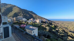 Un village côtier aux maisons traditionnelles en pierre, offrant une vue dégagée sur la mer et s’étendant au pied de montagnes.