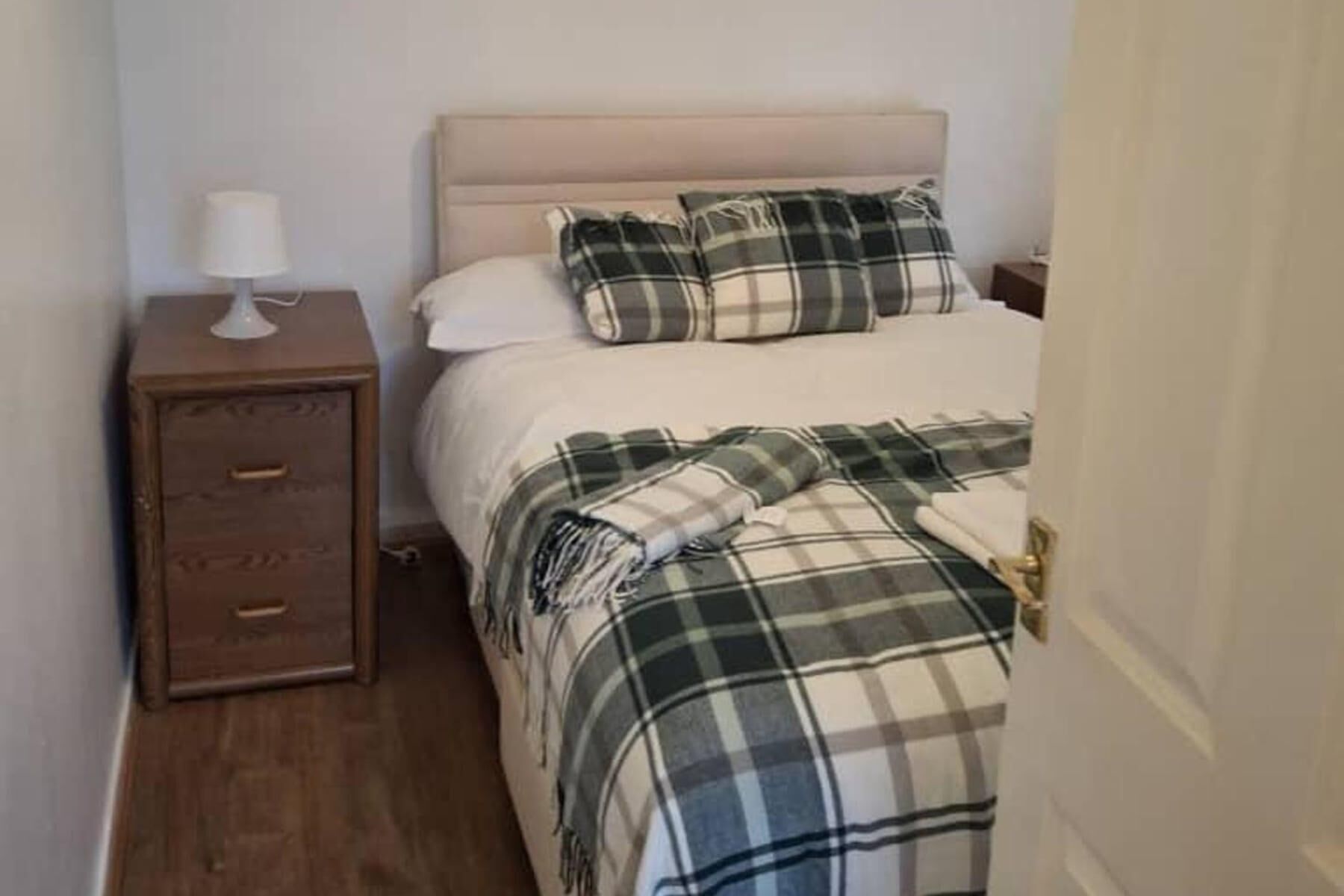 Quarto com cama, mesa de cabeceira e porta.