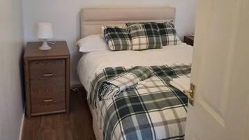 A bedroom with a bed, a nightstand, and a door.