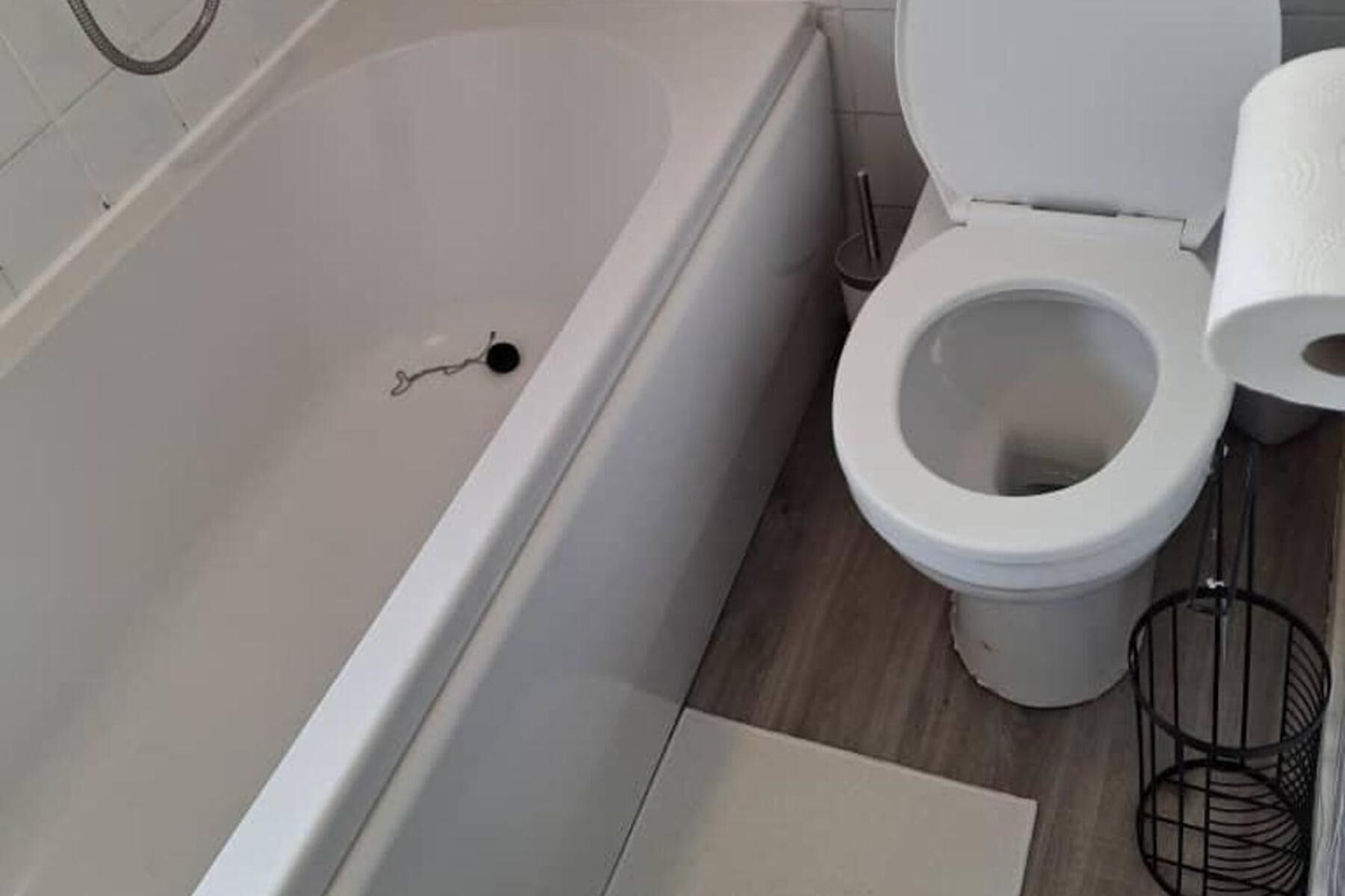 Une salle de bain avec une baignoire, des toilettes et une petite poubelle.