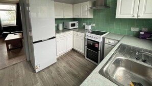 A modern kitchen with white cabinets, a built-in microwave, a stove, and a sink. - 3 Bed House Sleeps 5 - Free Parking - Tv & Wifi (Sheffield)