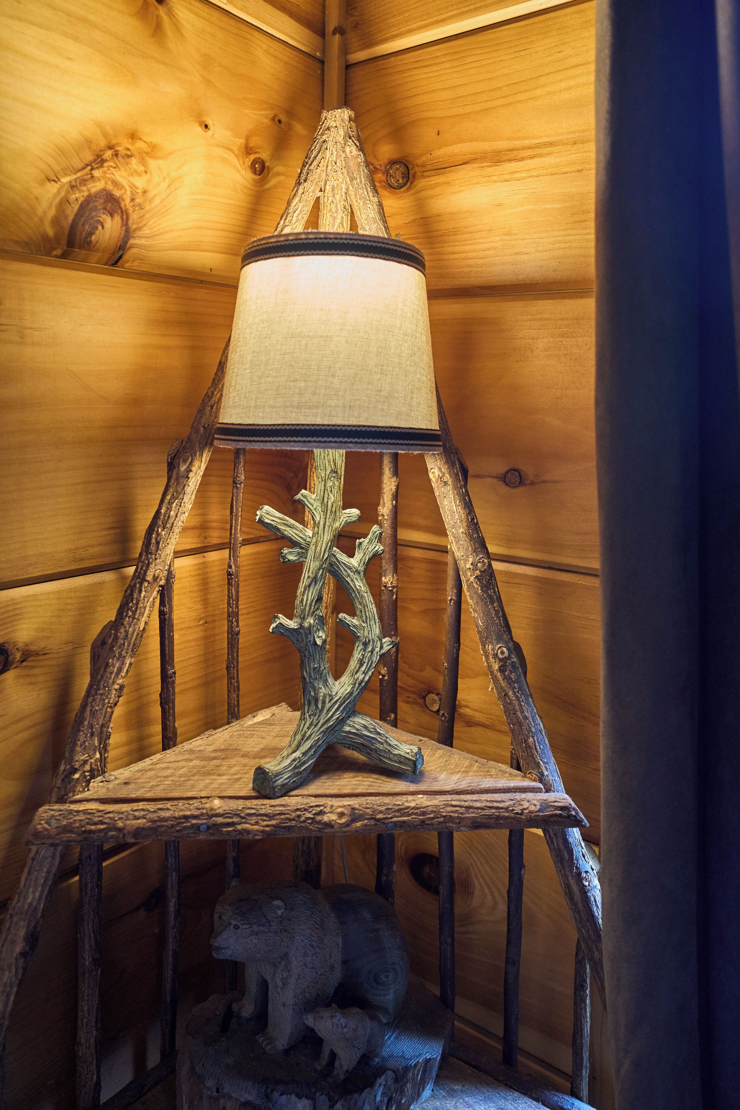Una lámpara de madera rústica con pantalla texturizada y una base con forma de árbol.