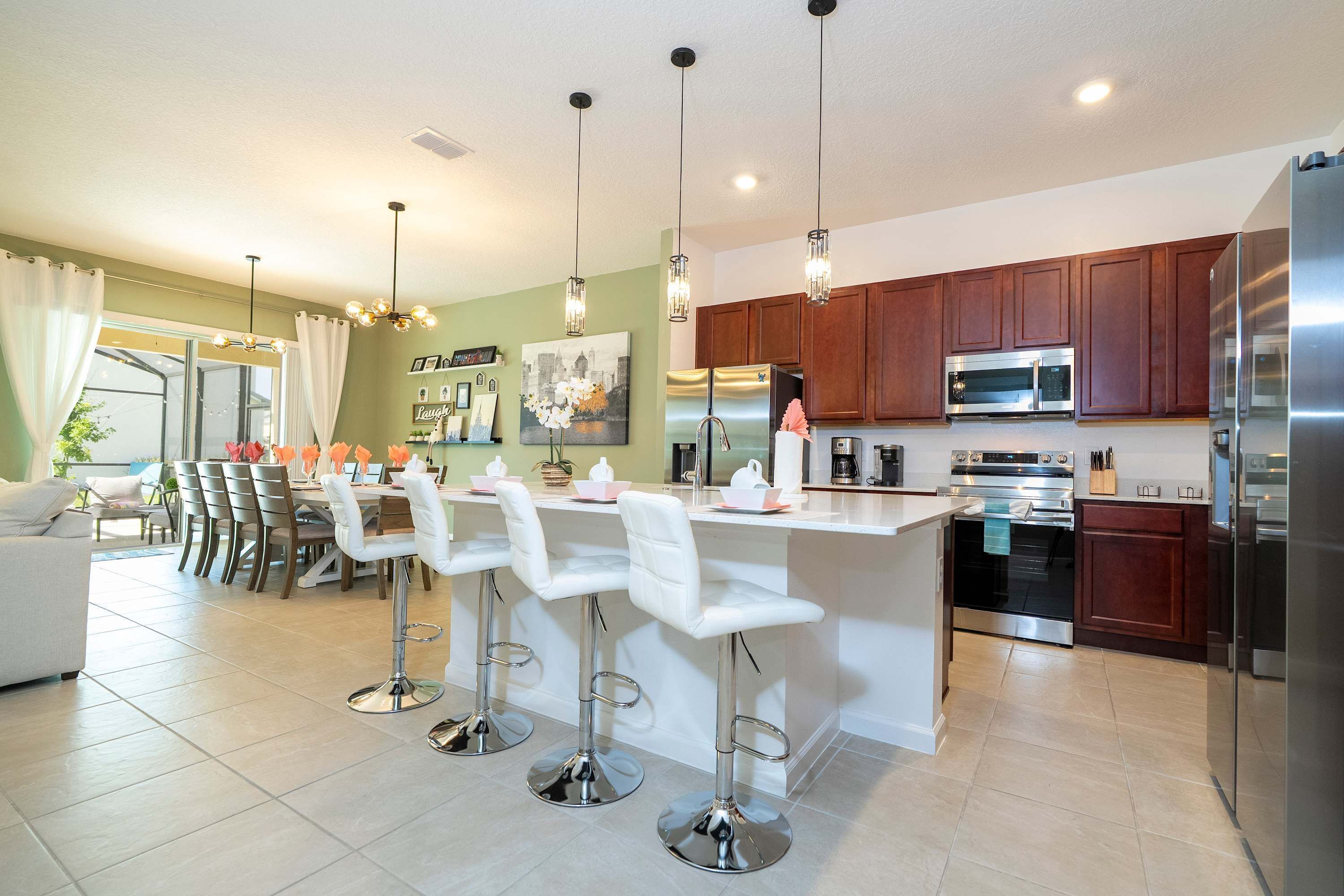 A modern kitchen with stainless steel appliances, a central island with bar stools, and wooden cabinets.