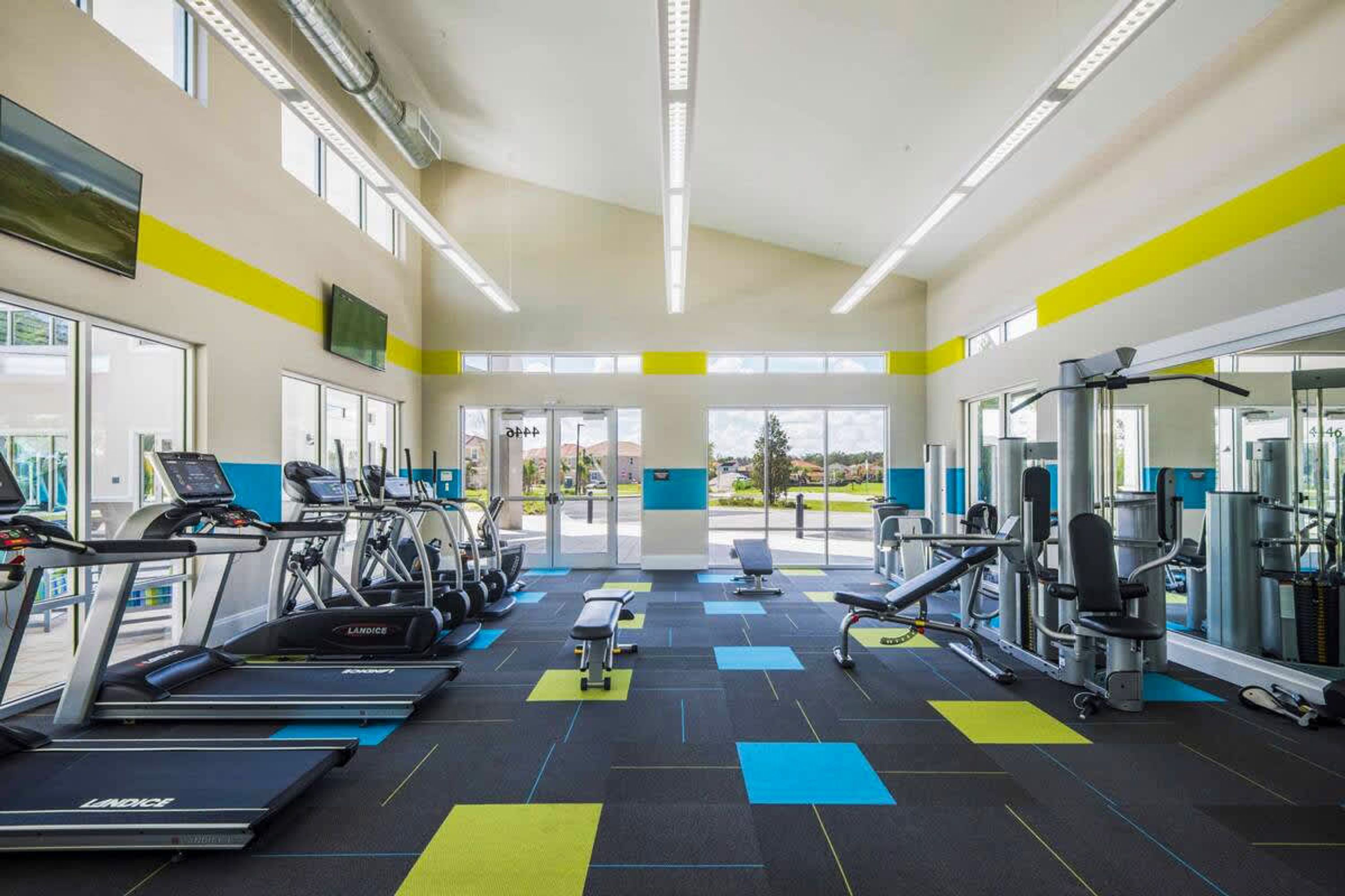 A gym with treadmills, weight machines, and a bench.