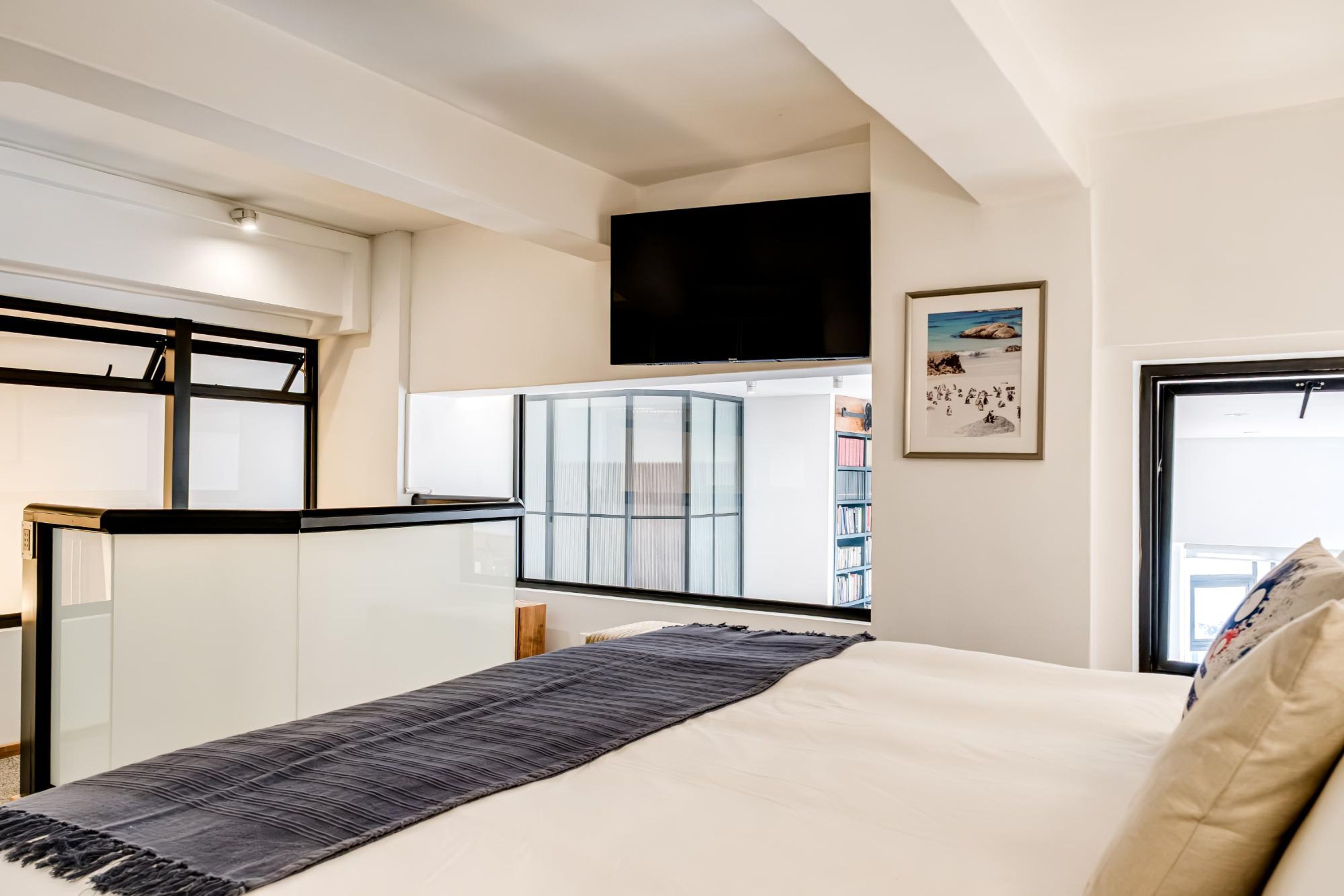 Une chambre moderne avec un grand lit, un téléviseur à écran plat fixé au mur et une fenêtre donnant sur l’extérieur.
