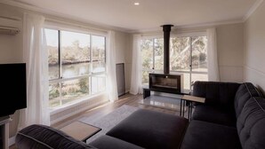 A modern living room with a fireplace, large windows, and a sofa.