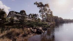 A house by a lake with a wooden deck and a chimney.