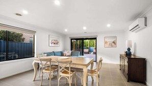 A dining area with a wooden table and chairs, a sofa, and a cabinet. - Family-Friendly 4BR Mount Duneed Manor (Mount Duneed)
