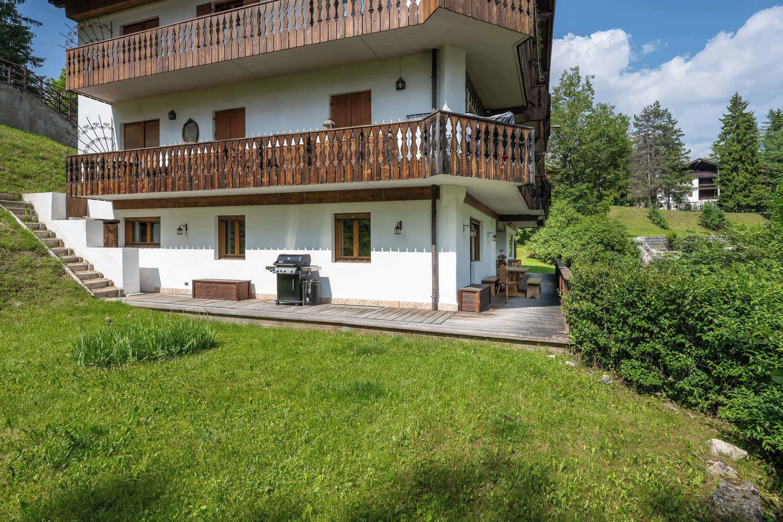 Ein mehrstöckiges Gebäude mit einem hölzernen Balkon, Sitzgelegenheiten im Freien und einem Grill.