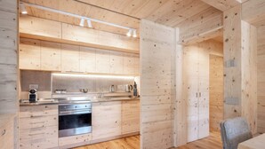 Een moderne keuken met houten kastjes, een roestvrijstalen fornuis en een eethoek met tafel en stoelen.
