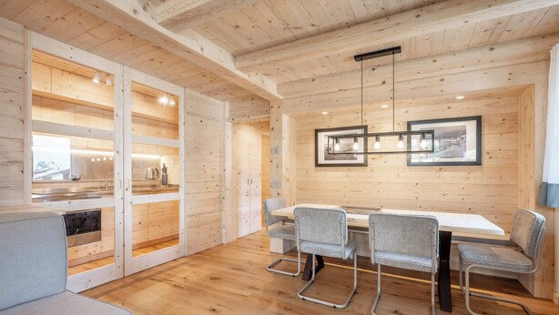 Een modern houten interieur met een eethoek, een inbouwkeuken en een groot raam.