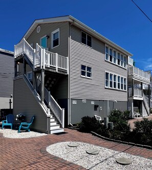 A multi-story building with a staircase leading to a balcony, a parking sign, and outdoor seating.